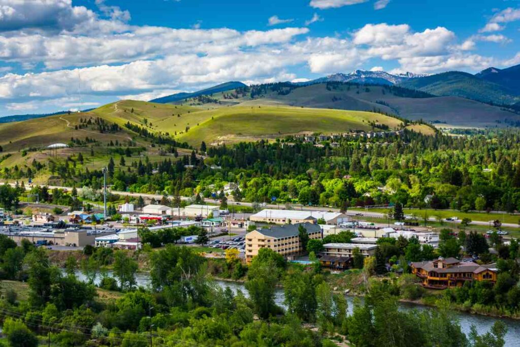 Buildings in Missoula in front of green hills and mountains.