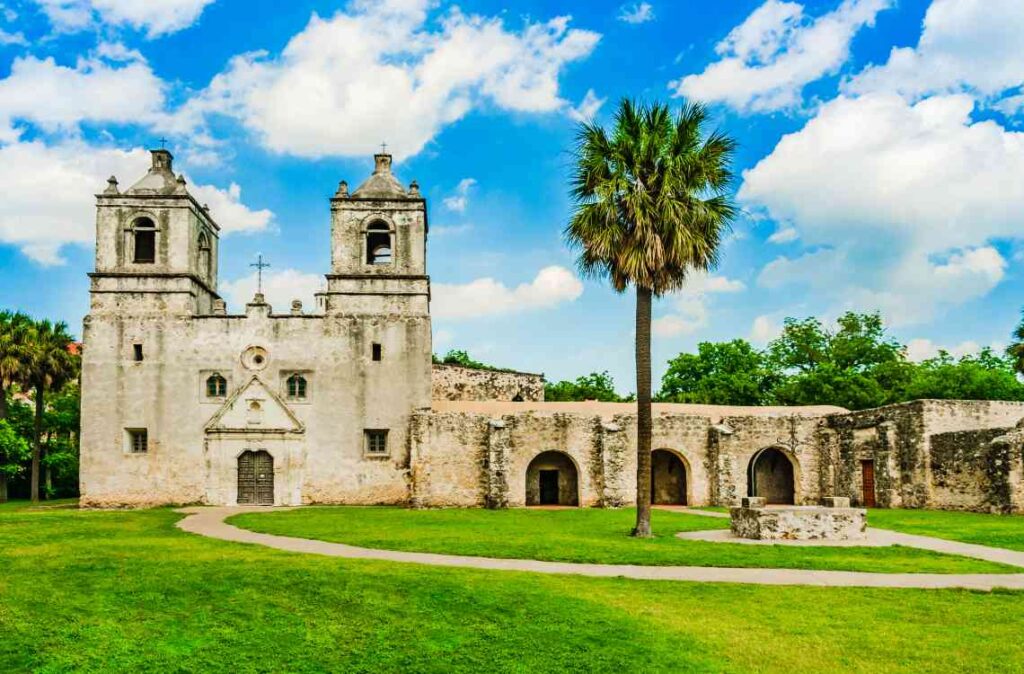 Historic spanish-style church with palm trees and blue skies