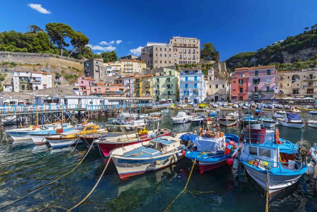 fishing boats in a marina in front of colorful houses