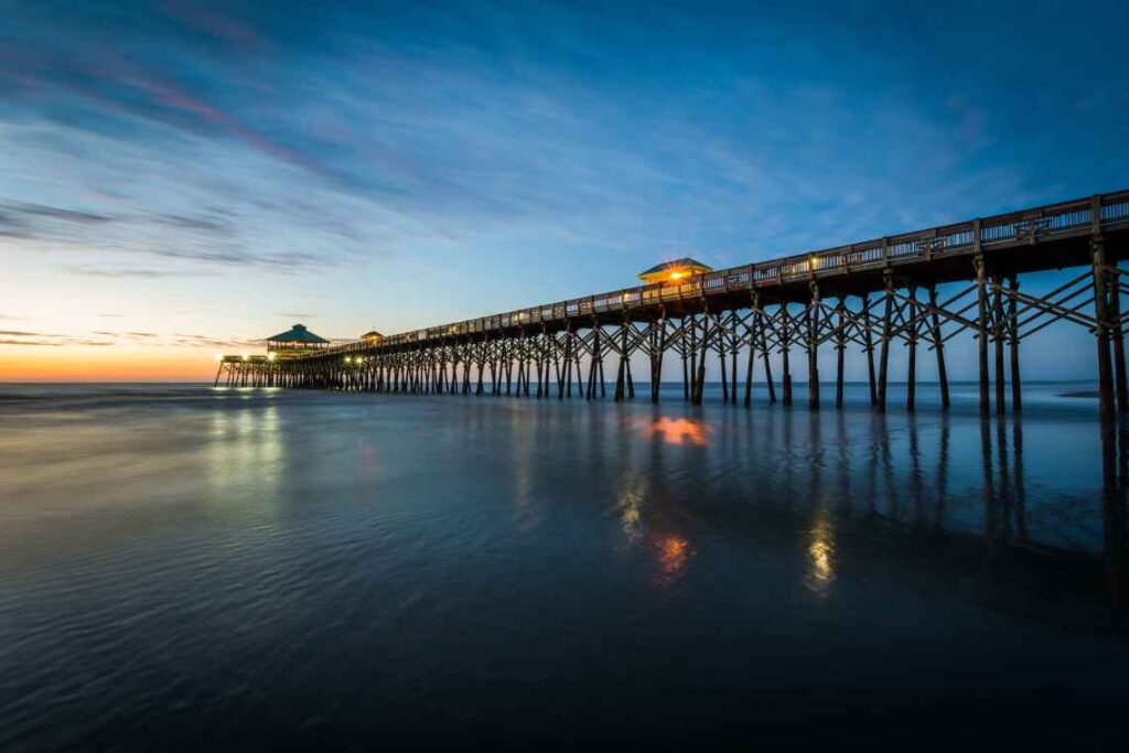 long boardwalk stretching into the ocean at sunrise at folly beach near charleston, sc 