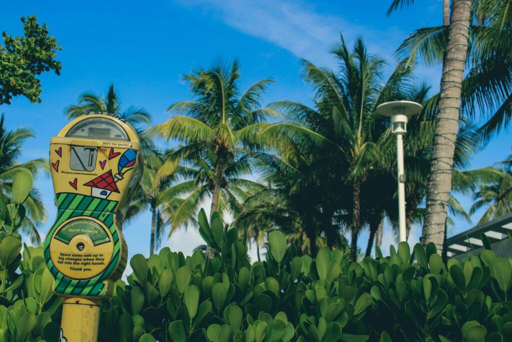 A parking meter next to a lush green forest in Miami