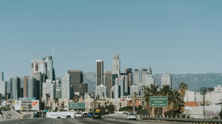 A multi-lane Los Angeles freeway leading toward the downtown skyline on a clear day