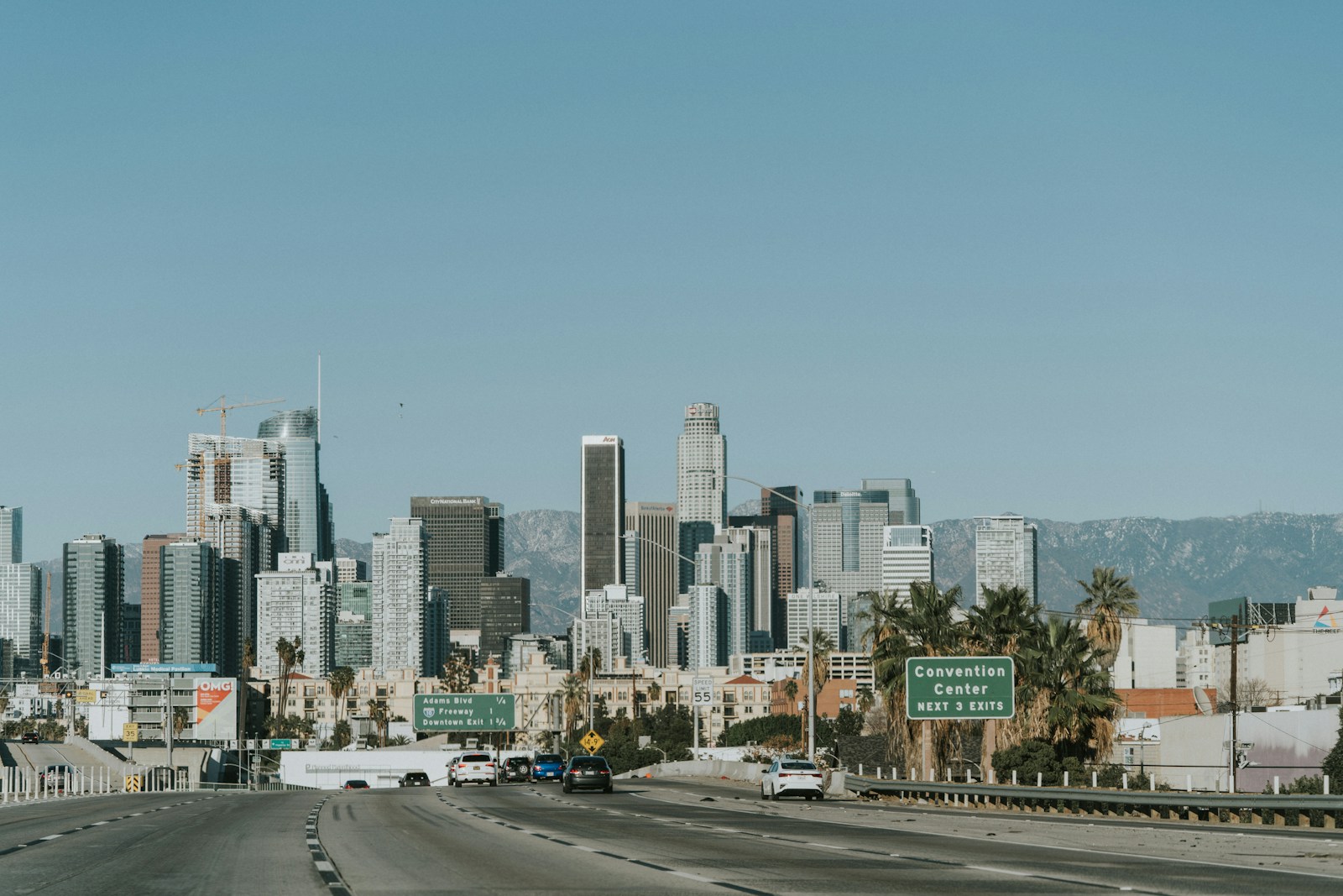 A multi-lane Los Angeles freeway leading toward the downtown skyline on a clear day